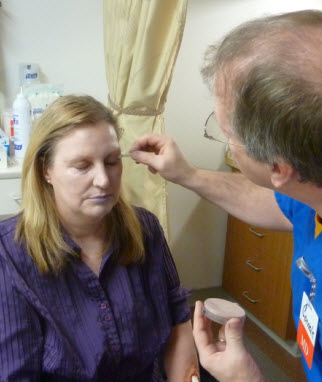 Instructor applying moulage makeup to a participant during a clinical simulation training session